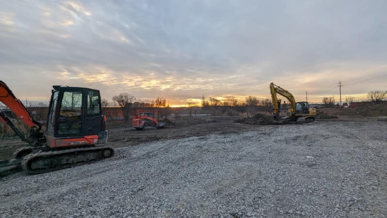 Grading a gravel road with heavy machinery at sunset
