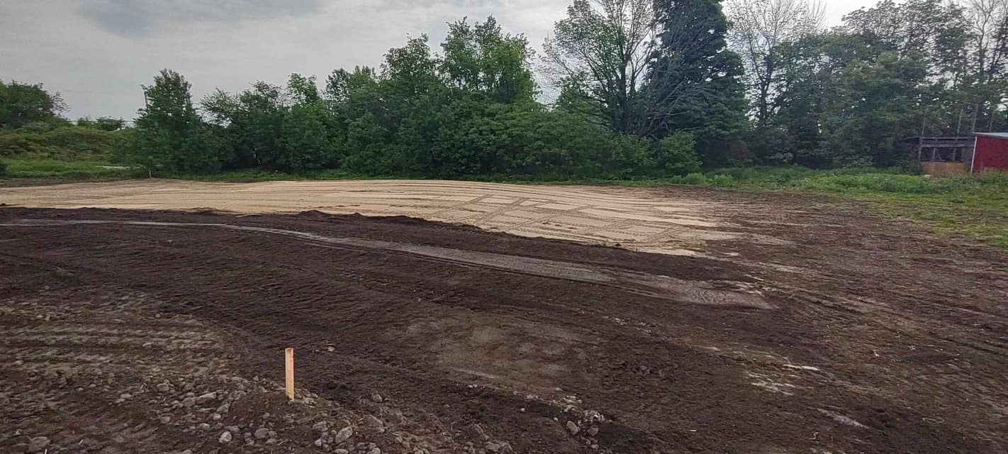 Freshly prepared site with layers of sand and good soil spread for grading, showing the foundation work before landscaping or construction.