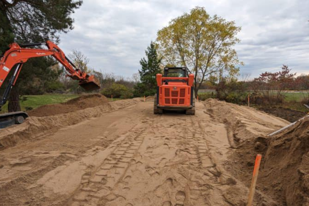 Excavation and rough grading underway with excavator and track loader shaping the septic bed area.