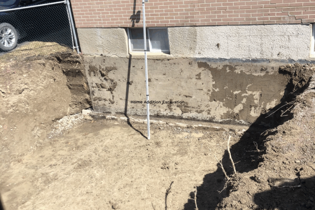 Foundation wall exposed by excavation, marked for a home addition installation.