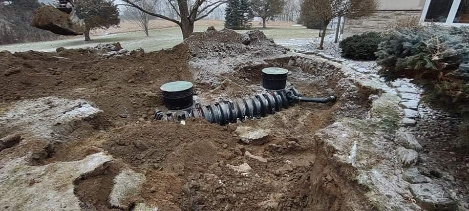 A septic tank in the ground surrounded by soil and frost.
