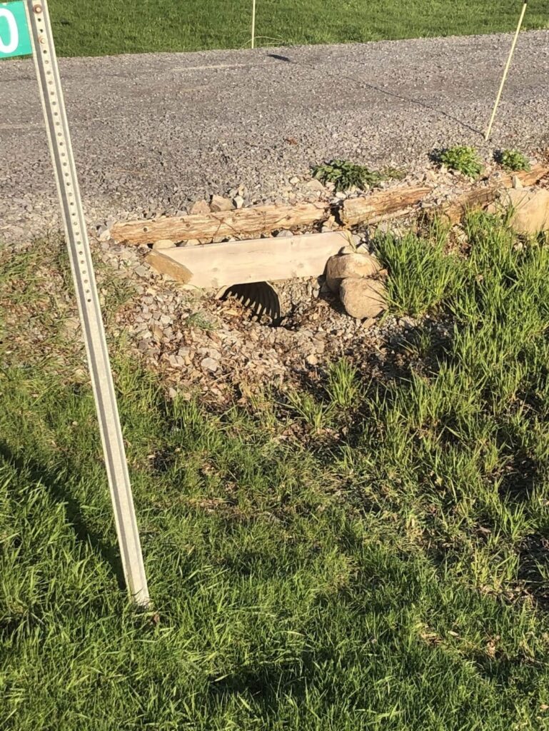 Partially blocked culvert for a driveway.