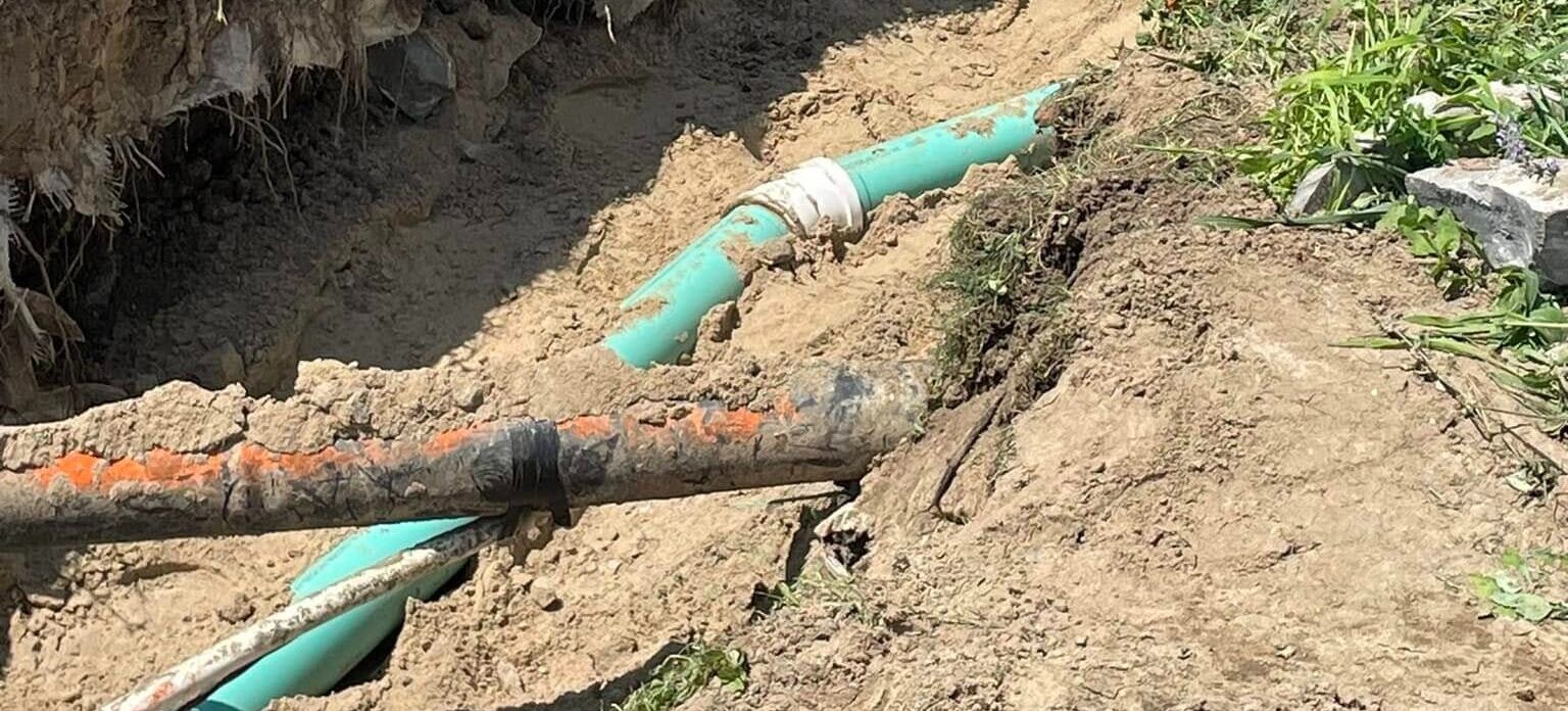 Sewer line pipes exposed in soil.