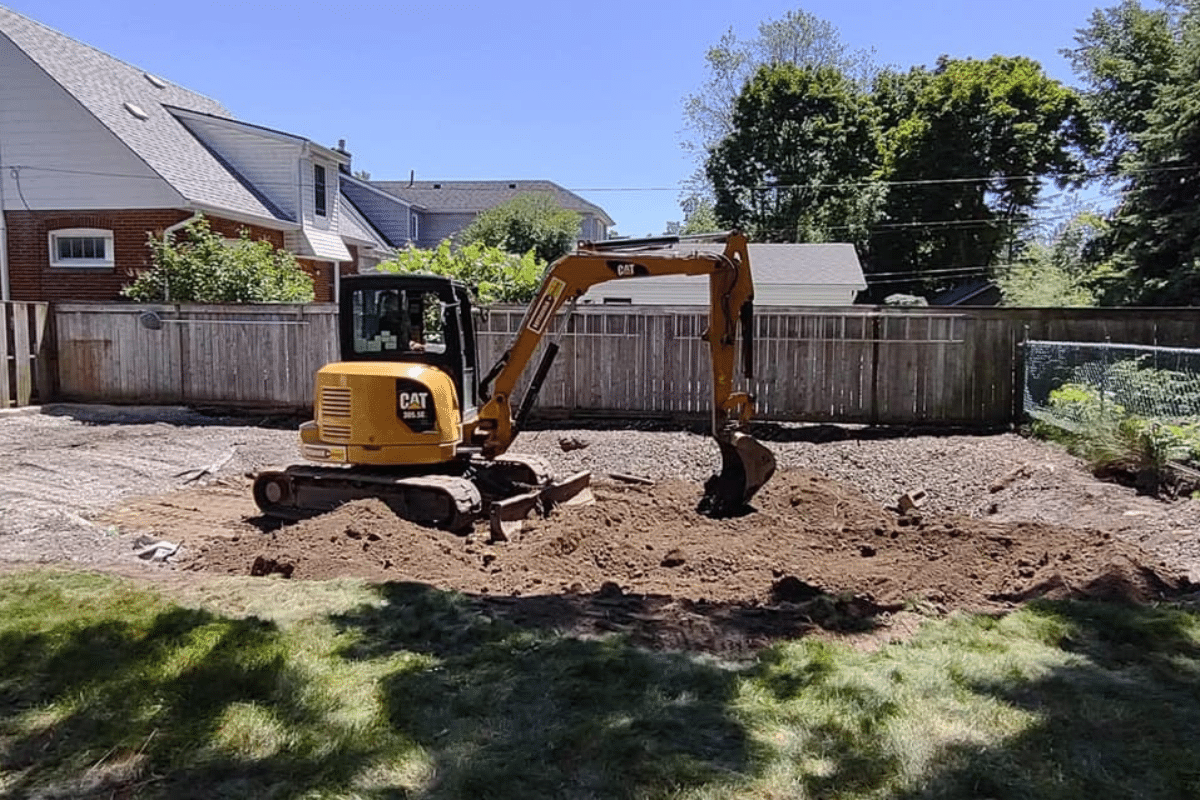 An excavator grading soil overtop of gravel.