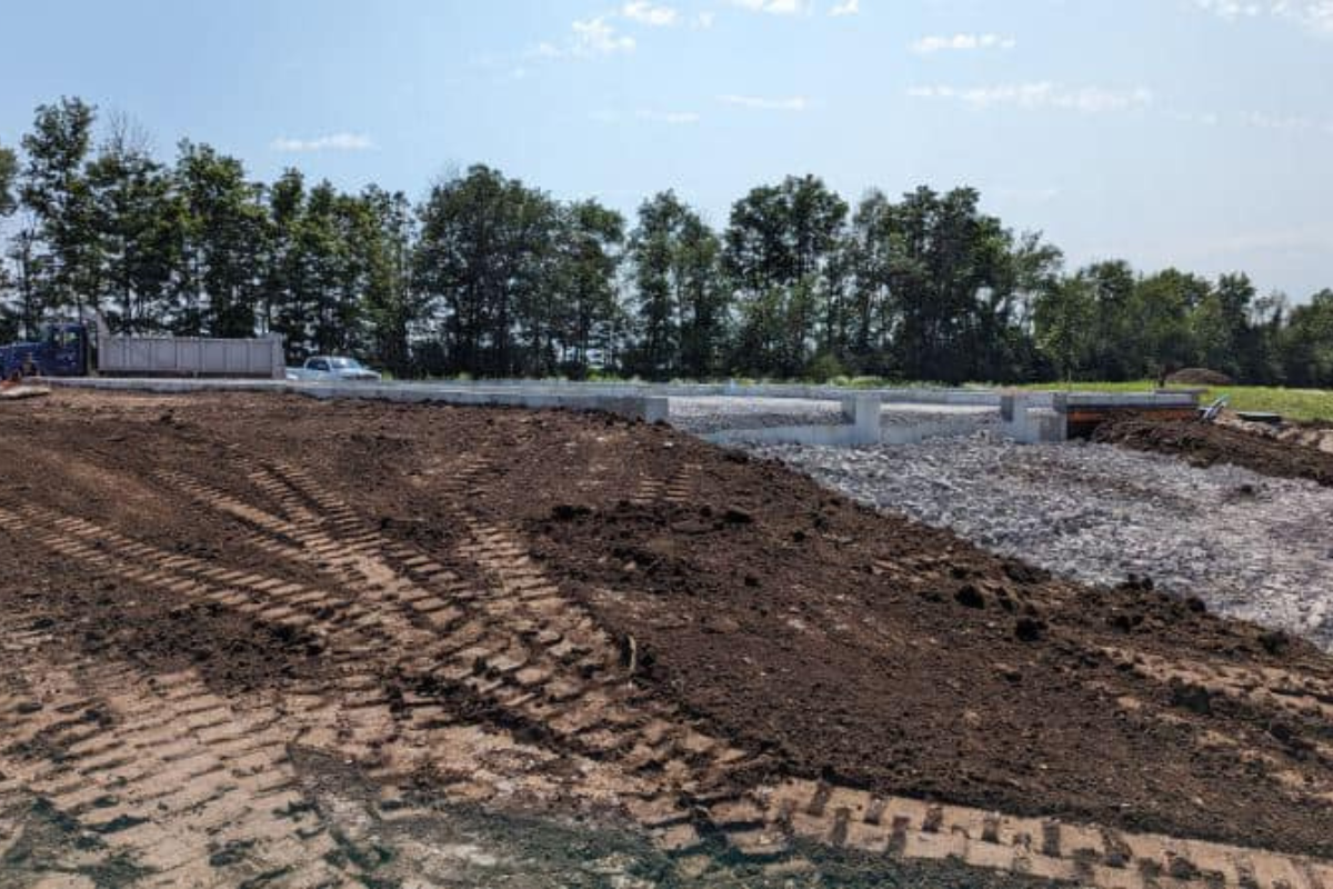 Soil graded around a newly set foundation for a home.